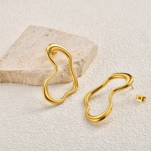 Detailed macro view of gold-plated irregular U-shaped earrings on stone background