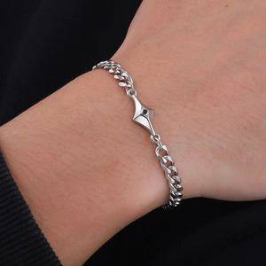 Detail view of men's silver Cuban link bracelet with star charm and black stone inlay
