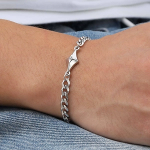 Close-up of stainless steel Cuban link bracelet with diamond-set geometric charm on wrist