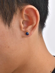 Detailed close-up of a blue lapis lazuli stone earring in gold base on male ear