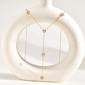 Dettaglio di una collana a Y dorata con cinque pendenti a cuore in zirconia cubica