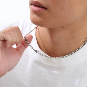 Detail of silver Cuban chain necklace with minimalist diamond-shaped pendant on neck
