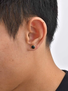 Close-up of a men's round gold-plated earring with a black onyx-style inlay on ear