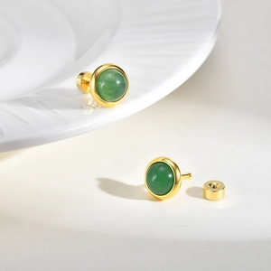 Detail of round green gemstone stud earrings with elegant gold metal plating