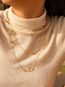 Dettaglio della collana doppia dorata con pendente rotondo e maglie con cristalli lucidi
