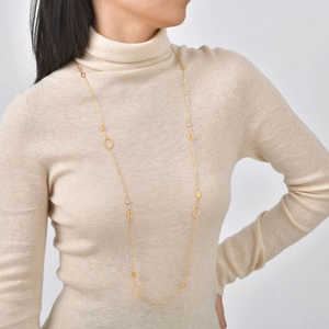 Dettaglio di una collana a Y dorata minimalista con perle finte e zirconi cubici rotondi