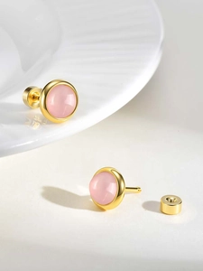 Detail of round gold stud earrings featuring pink stones and secure screw-back posts