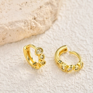 Detailed view of golden huggie hoop earrings with mixed-cut cubic zirconia on stone
