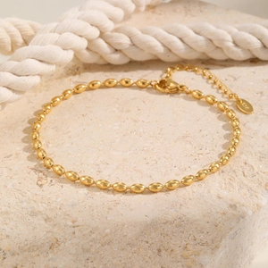 Detailed macro shot of the 18K gold plated bead chain anklet and lobster clasp on stone