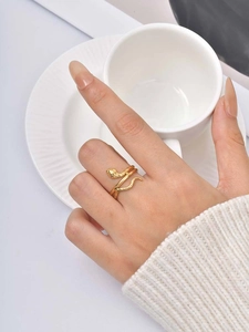 Golden snake-shaped ring with textured surface worn by a model in a minimal setting