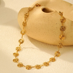 Macro detail of golden spiral link necklace showing twisted wire texture and shiny finish