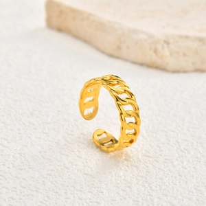 Macro shot of gold-plated stainless steel chain link ring on white textured surface