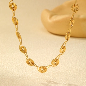 Detail of a gold spiral link chain necklace with minimalist geometric wire wrapping