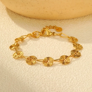 Macro view of gold geometric spiral links on stainless steel bracelet with lobster clasp