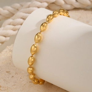 Detailed view of polished golden oval bead chain wrapped on a minimalist cylinder