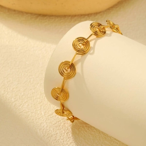 Detailed close-up of a gold-plated stainless steel spiral link bracelet on a display stand