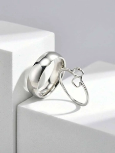 Close-up of dual heart-shaped silver rings set on a minimalist white stone pedestal