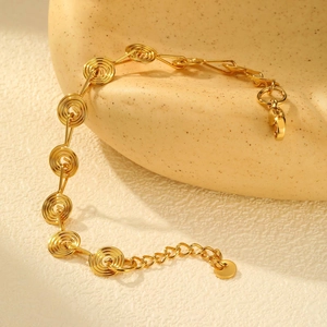 Detail of a golden spiral link bracelet with adjustable lobster clasp on ceramic