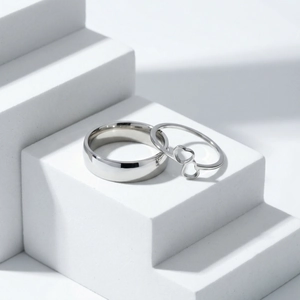 Macro detail of high-polished stainless steel double heart rings on geometric steps