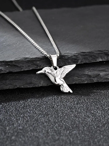 Detailed view of polished stainless steel hummingbird pendant on a delicate box chain