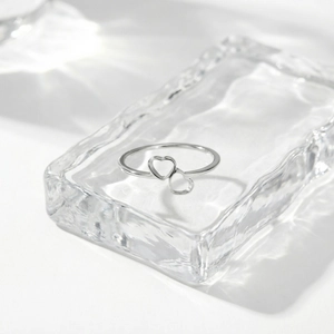 Macro detail of silver stainless steel ring featuring double hollow heart design on water ripple