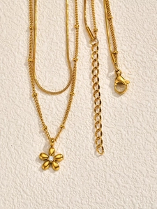 Detailed view of a gold double-layer chain with floral pendant and sparkling center stone