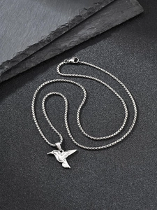 Macro detail of a silver hummingbird pendant with intricate feather textures on a dark chain