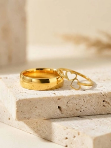 Close-up of gold stainless steel ring set with double heart design on travertine stone