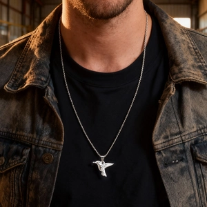 Minimalist silver hummingbird pendant necklace on male model with dark vintage denim jacket
