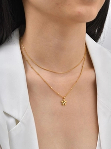 Close-up of gold double-layer necklace with snake chain and diamond-set flower pendant