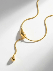 Détail d'un collier lariat minimaliste en or 18 carats avec maille serpent et goutte d'eau