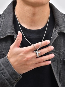 Detailed view of humming bird necklace pendant on a model with grey denim jacket