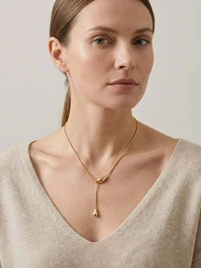 Gros plan d'un collier en Y doré élégant avec pendentif goutte sur une femme