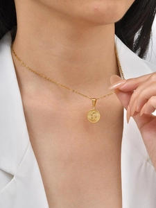 Gros plan d'un pendentif pièce dorée avec serpent gravé sur une chaîne fine