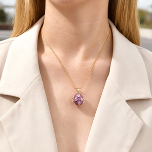 Close-up of a purple enamel Faberge style egg pendant necklace with gold grid pattern