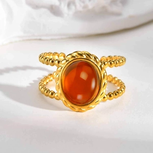 Macro detail of golden double-beaded ring band with oval orange stone inlay