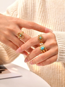 Detailed close-up of bohemian triple gold rings set with turquoise on a hand