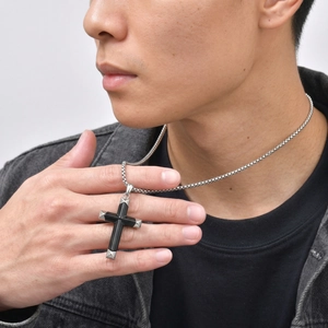 Men's stainless steel necklace with black onyx cross pendant worn on denim jacket