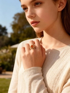Detail of a vintage double-layer gold rope ring with an oval reddish gemstone on finger