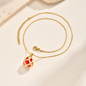 Macro detail of red and white lattice egg pendant with crystal accents on gold chain