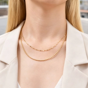 Close-up of double-layered gold stainless steel necklaces on a beige suit model