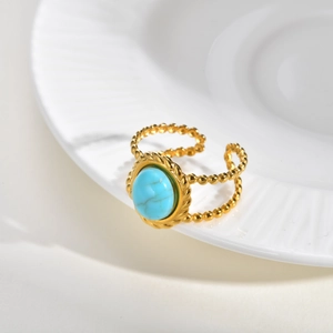 Close-up of golden boho ring with turquoise stone on white ceramic plate edges