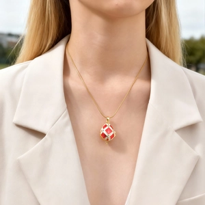 Detail view of a vintage red and white enamel egg pendant with diamonds on a gold snake chain