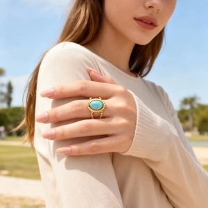 Detail of bohemian gold woven ring featuring a large oval turquoise stone worn outdoors