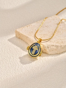Macro shot of an opening blue enamel egg locket with a crystal cross on a stone surface