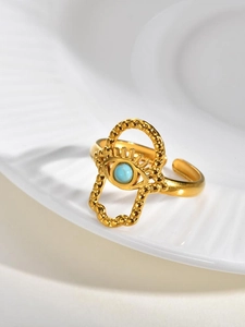 Detailed macro view of gold Hamsa Hand ring featuring a turquoise stone and textured metal