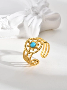 Detail shot of a bohemian gold-plated ring featuring turquoise inlay and hollow carving