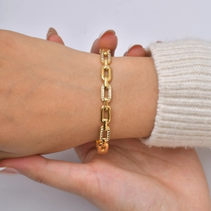 Detailed view of 18K gold chain bracelet with sparkling zircon pavé on a model's wrist