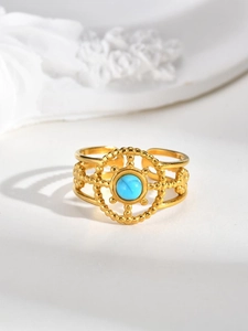Macro detail of gold open ring featuring a turquoise stone and hollow sunburst design
