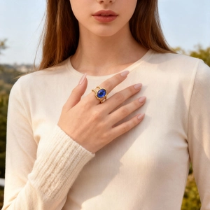 Detail of vintage gold braided ring featuring a large oval deep blue gemstone on a finger